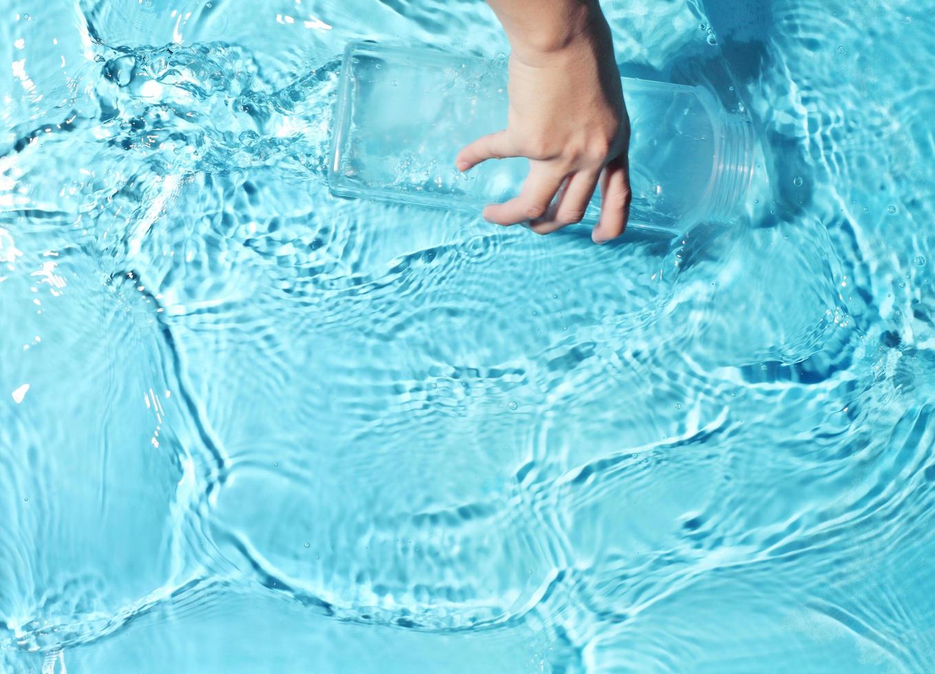 Frau benutzt Plastikflasche, um klares Wasser zu schöpfen foto