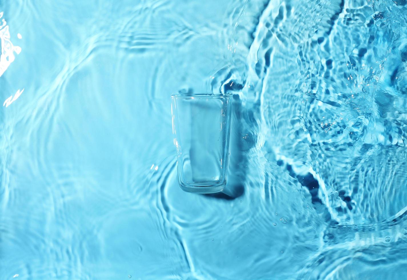 leeres Glas schwimmt auf klarem Wasser foto