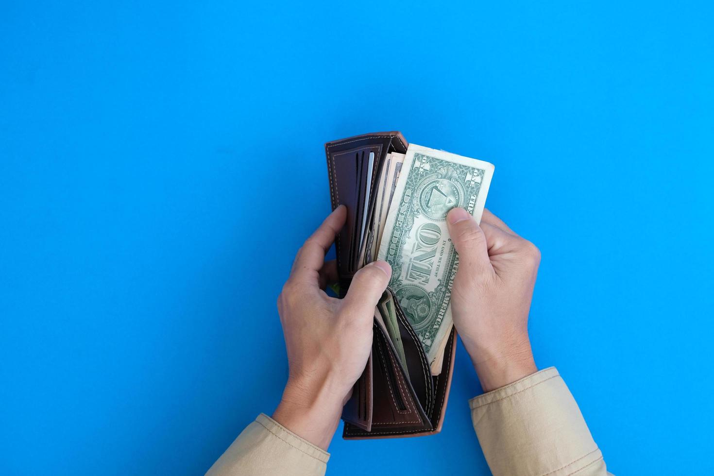 Finanzen und Bankwesen werden durch eine Hand dargestellt, die eine Banknote mit dem Konzept des Geldes auf blauem Hintergrund hält. foto
