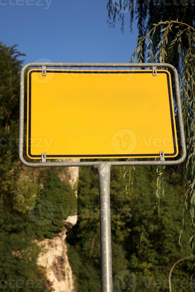 gelbes Straßenschild auf einem Hintergrund von Bäumen foto