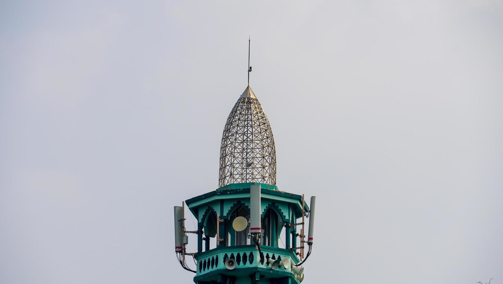 die Spitze eines Moschee-Minaretts mit einer Art indonesischer traditioneller Architektur. das Minarett enthält Lautsprecher als Lautsprecheraufruf zum Gebet. foto