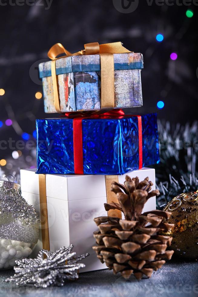 Frohe Weihnachten und ein glückliches neues Jahr-Konzept, Weihnachtshintergrund mit Bokeh-Licht und verschwommen. Weihnachtsgeschenk mit Christbaumschmuck und Zapfen auf dunklem Holzhintergrund im Vintage-Stil foto