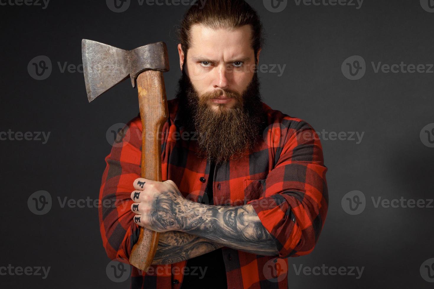 gut aussehender Mann mit langen Haaren mit einer Axt in den Händen auf dunklem Studiohintergrund foto