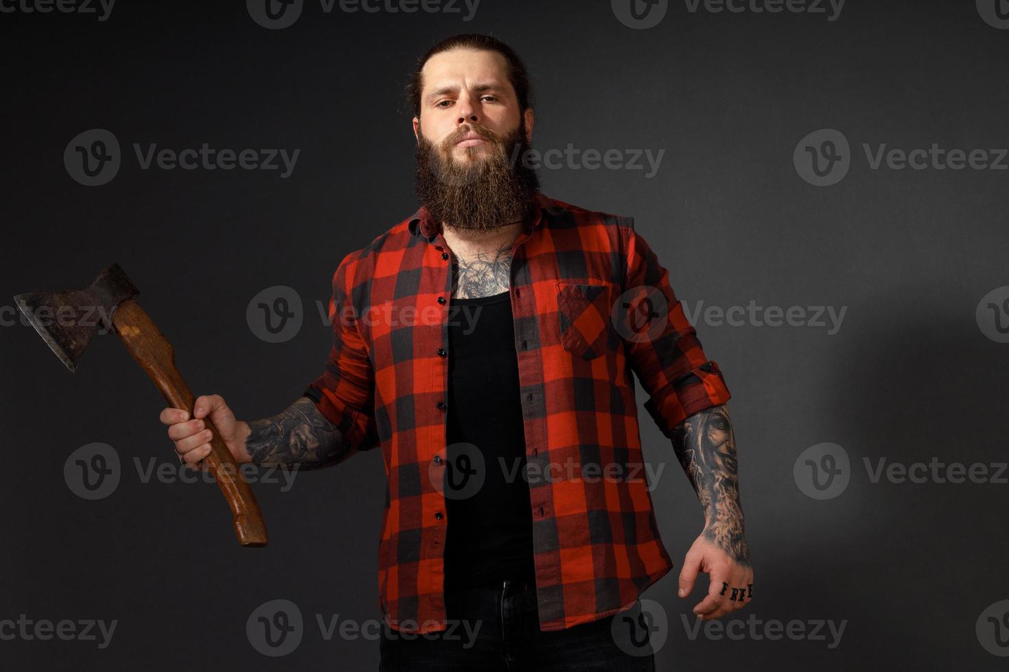 gut aussehender Mann mit langen Haaren mit einer Axt in den Händen auf dunklem Studiohintergrund foto