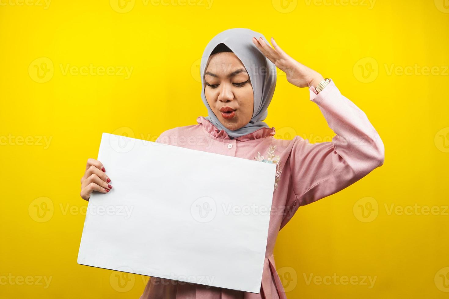 hübsche junge muslimische Frau schockiert, wow, Hand, die leeres leeres Banner, Plakat, weiße Tafel, leeres Schild, weiße Werbetafel hält, etwas im Kopierraum präsentiert, Werbung foto