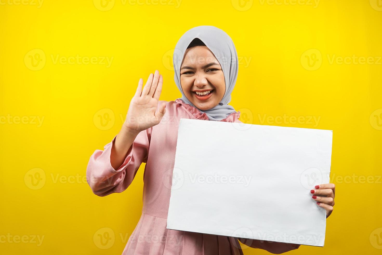 hübsche junge muslimische Frau, die fröhliche leere leere Banner, Plakate, weiße Tafeln, leere Schilder, weiße Werbetafeln hält, etwas im Kopierraum präsentiert, Werbung foto