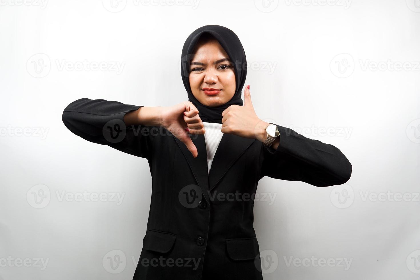 schöne asiatische junge muslimische Geschäftsfrau mit Handzeichen wie oder Abneigung, ja oder nein, glücklich oder traurig, zwei Dinge vergleichend, isoliert auf weißem Hintergrund foto