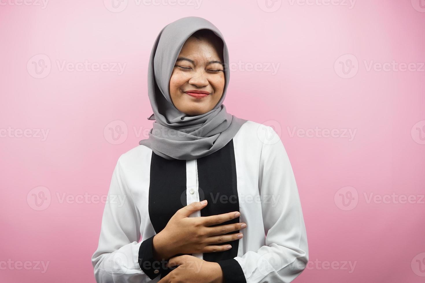 schöne junge asiatische muslimische frau, die fröhlich lächelt, mit den händen, die bauch halten, voller bauch, einzeln auf rosa hintergrund foto