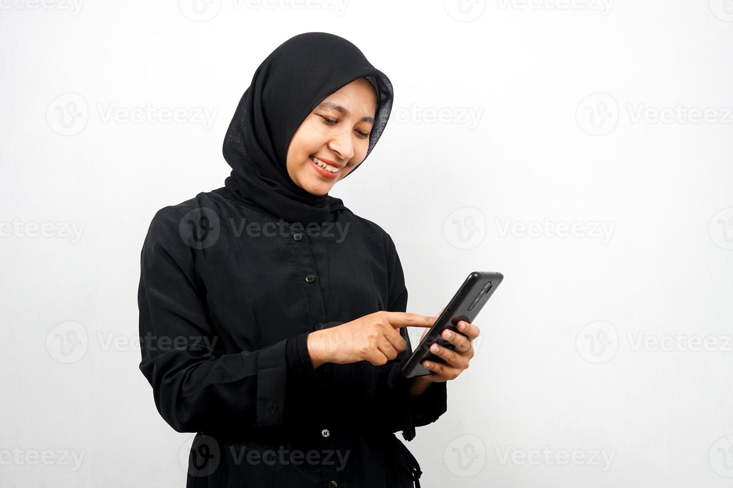 Schöne junge asiatische muslimische Frau mit Smartphone, selbstbewusst lächelnd, isoliert auf weißem Hintergrund, Werbekonzept foto