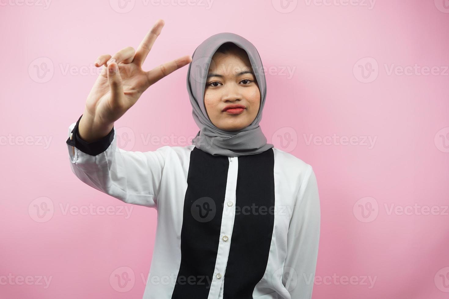 schöne junge asiatische muslimische frau schmollend mit v-signierten händen, ok, gute arbeit, vereinbarung, sieg, blick in die kamera einzeln auf rosa hintergrund foto