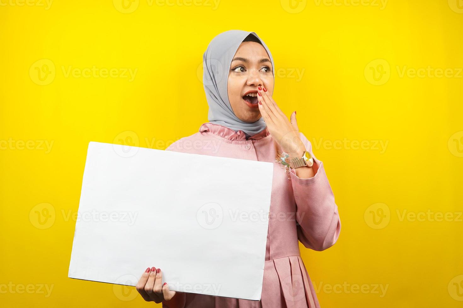 hübsche junge muslimische Frau schockiert, überrascht, wow, Hand, die leeres leeres Banner, Plakat, weiße Tafel, leeres Schild, weiße Werbetafel hält, etwas im Kopierraum präsentiert, Werbung foto