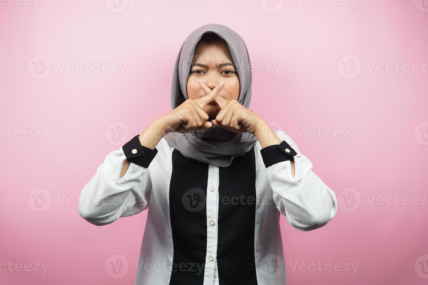 schöne asiatische junge muslimische frau mit finger auf dem mund, die sagt, sie solle leise sein, keinen lärm machen, die stimme senken, nicht sprechen, einzeln auf rosa hintergrund foto