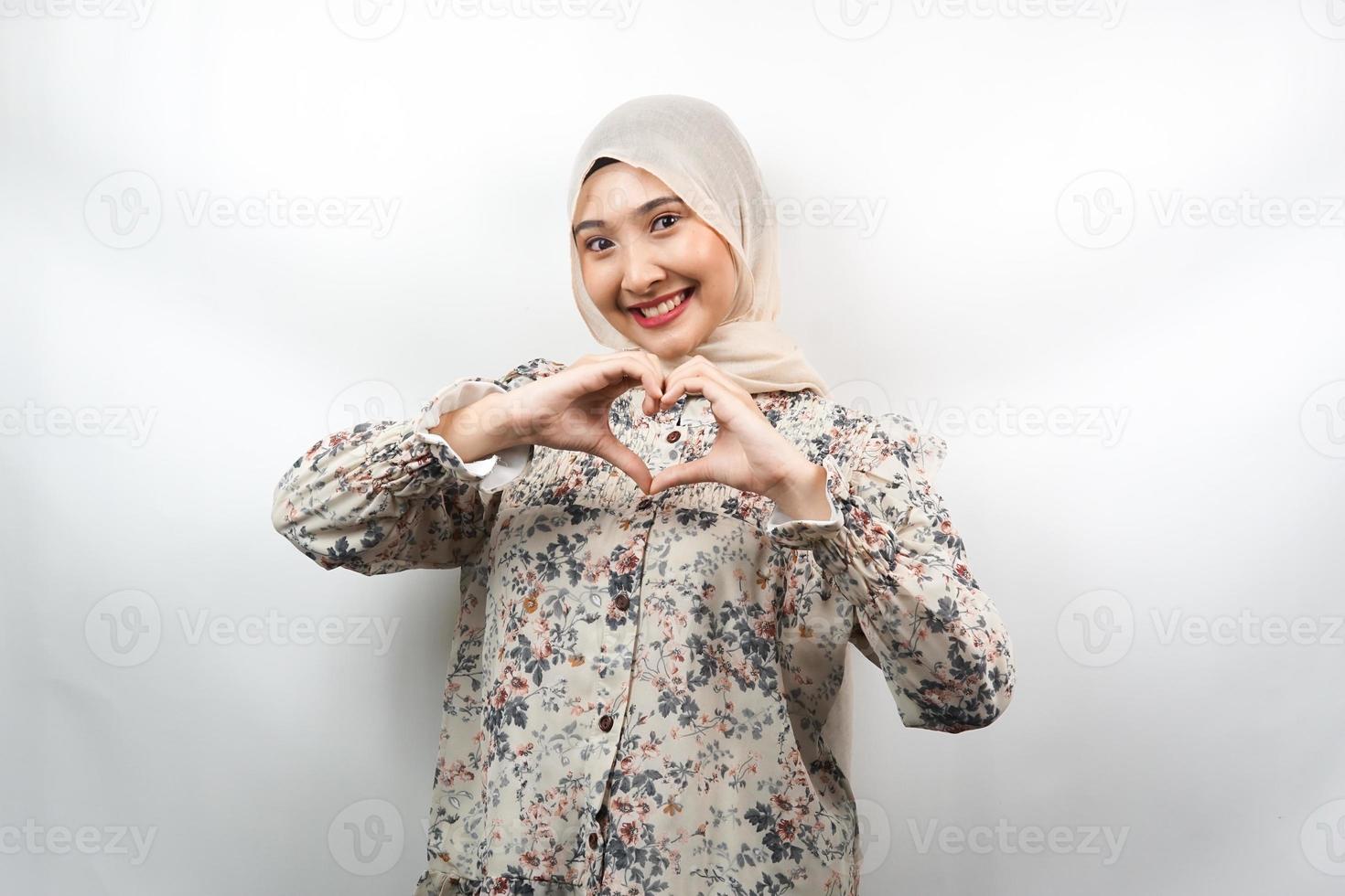 Schöne asiatische junge muslimische Frau, die selbstbewusst, enthusiastisch und fröhlich lächelt, mit Händen, Zeichen der Liebe, Zuneigung, glücklich, auf der Brust isoliert auf weißem Hintergrund foto