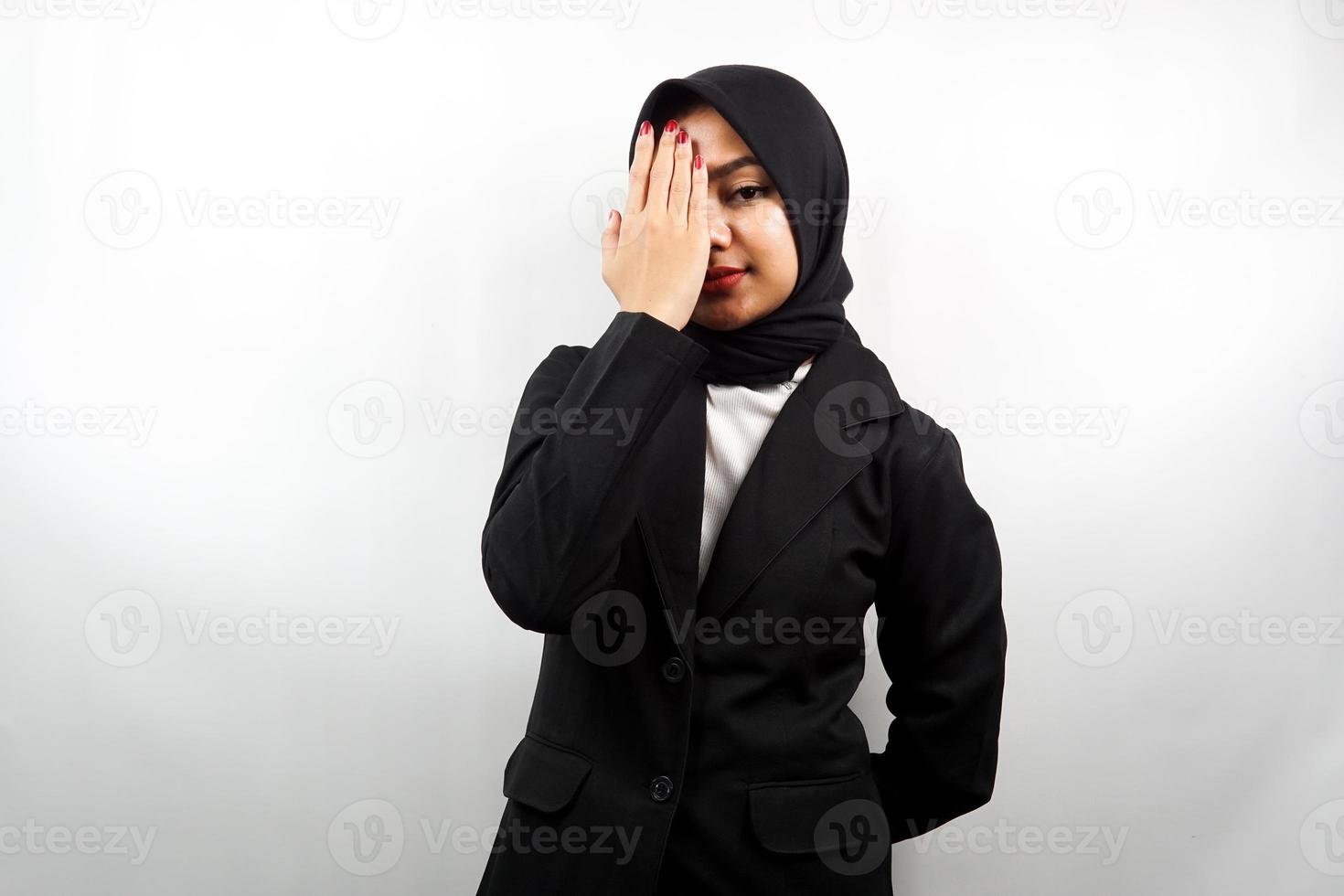 schöne asiatische junge muslimische Geschäftsfrau mit der Hand, die ein Auge bedeckt und in die Kamera schaut, die auf weißem Hintergrund lokalisiert wird foto