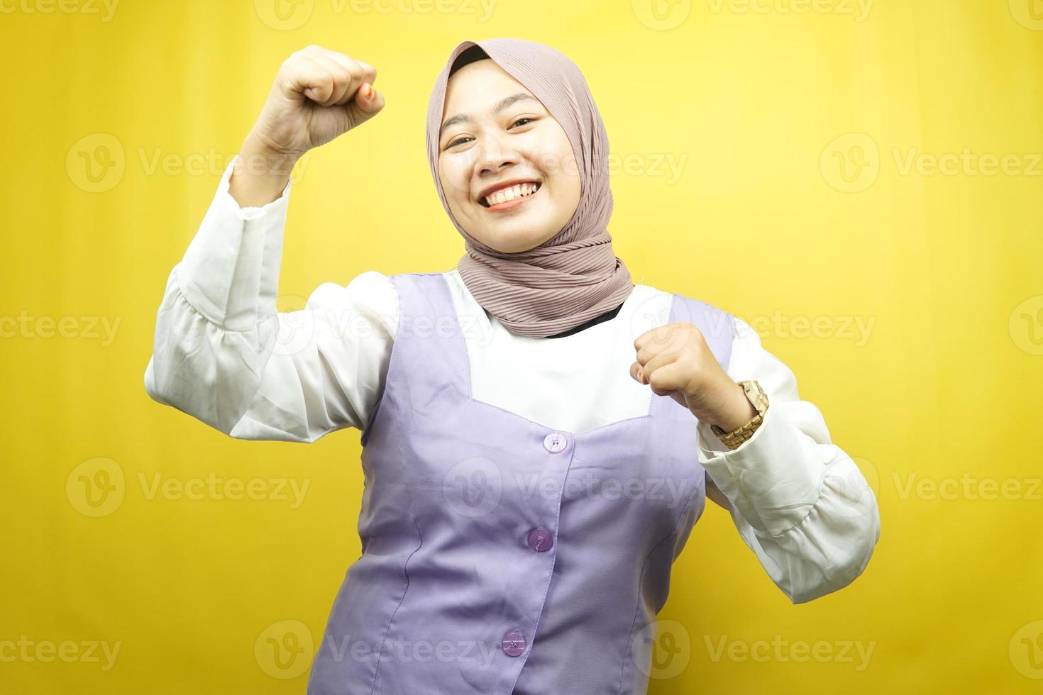 schöne junge asiatische muslimische frau, die selbstbewusst, enthusiastisch und fröhlich mit geballten händen lächelt, zeichen des erfolgs, schlagen, kämpfen, keine angst, einzeln auf gelbem hintergrund foto