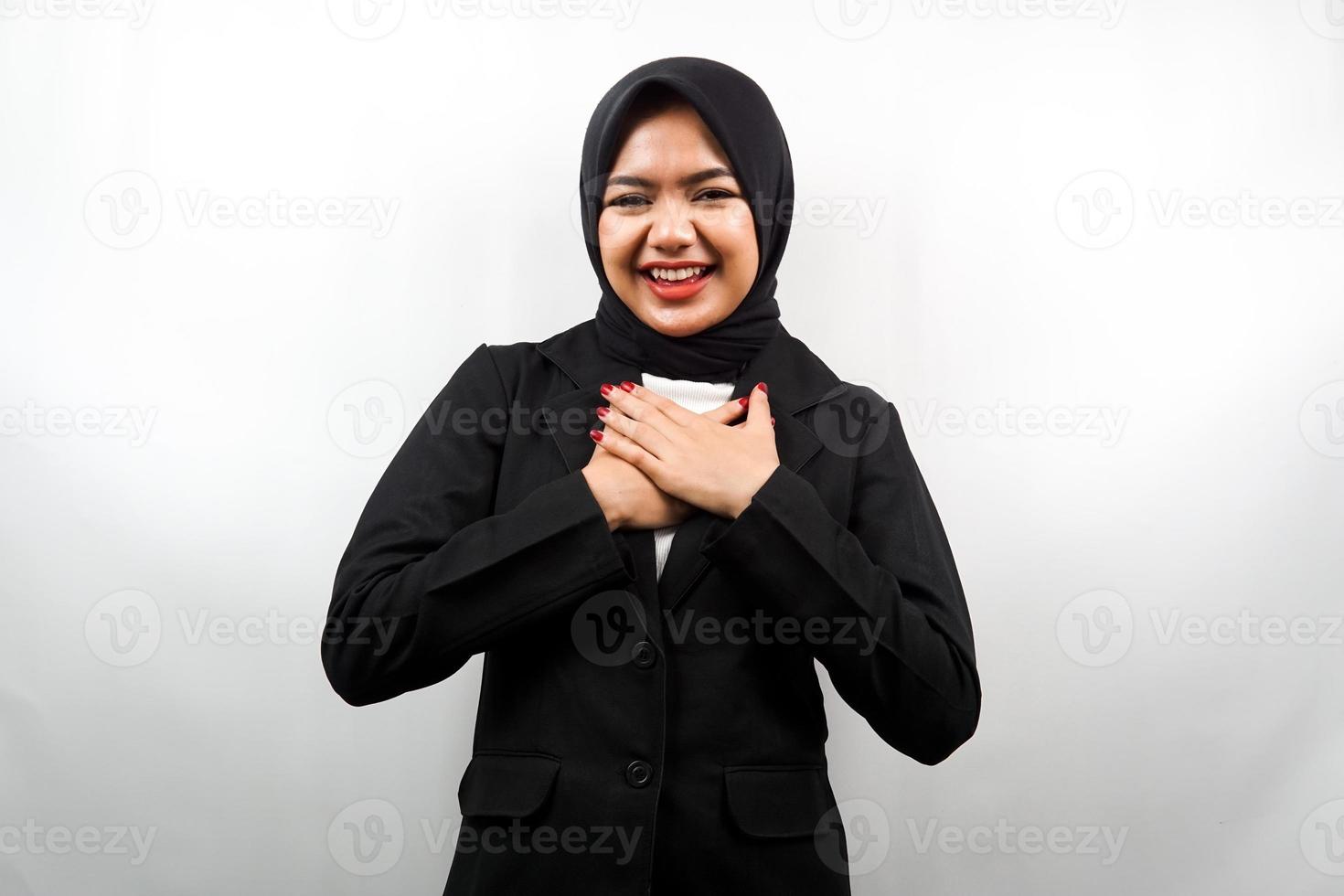Schöne junge asiatische muslimische Geschäftsfrau, die überrascht und fröhlich lächelt, mit den Händen, die die Brust halten, aufgeregt, nicht erwartet, mit Blick auf die Kamera isoliert auf weißem Hintergrund foto