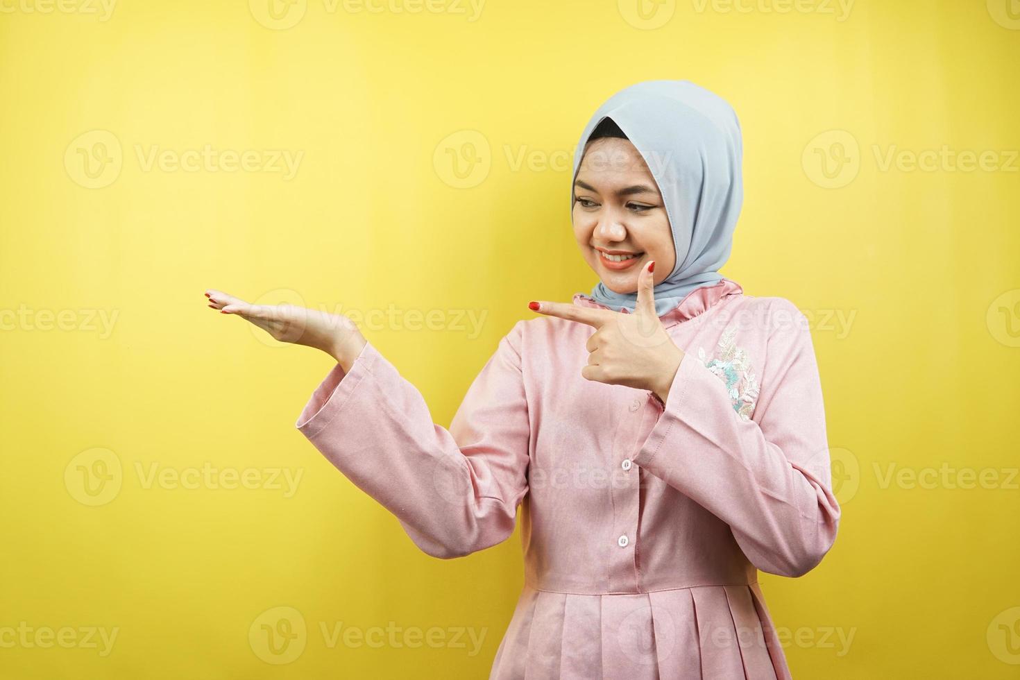 fröhliche schöne junge muslimische Frau, mit der Hand, die auf den leeren Raum zeigt, etwas fördert, isoliert foto