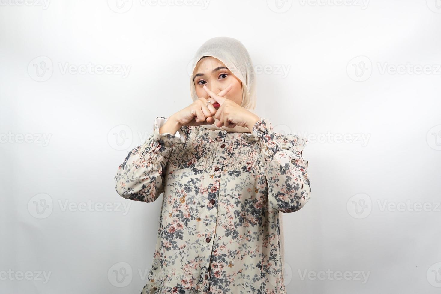 schöne asiatische junge muslimische frau mit finger auf dem mund, die sagt, sie solle leise sein, keinen lärm machen, die stimme senken, nicht sprechen, isoliert auf weißem hintergrund foto