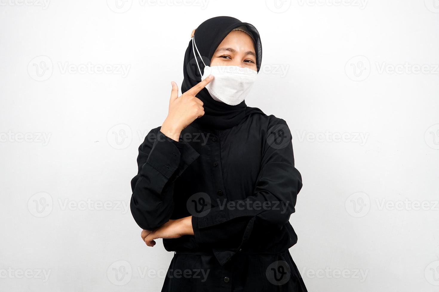 muslimische frau mit weißer maske, mit der hand, die auf maske zeigt, koronavirus-geste verhindern, covid-19 verhindern, isoliert auf weißem hintergrund foto