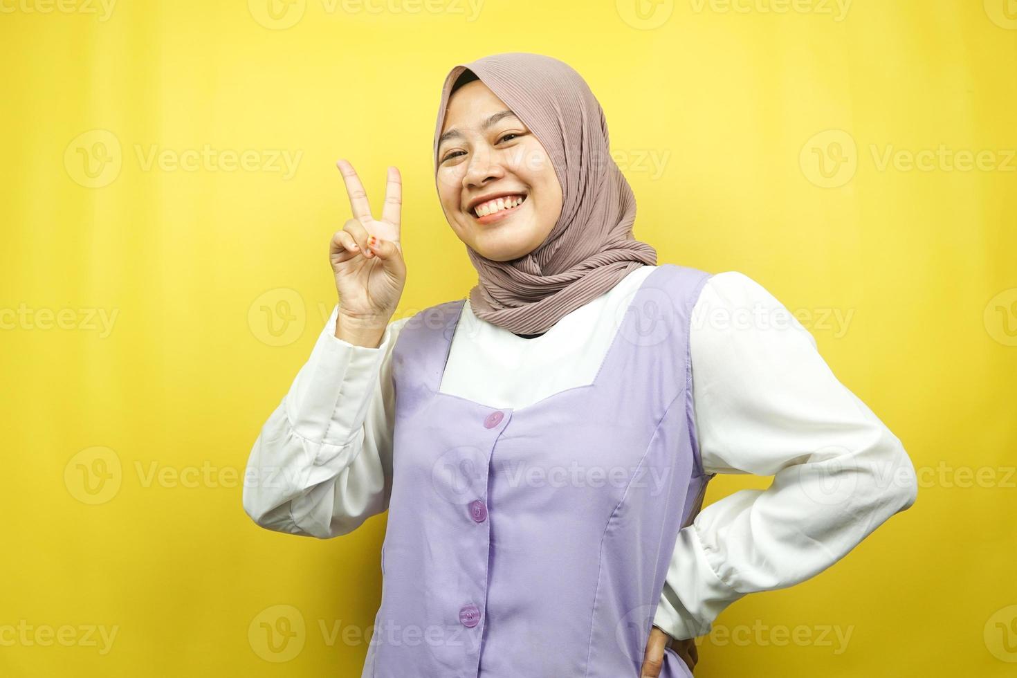 schöne junge asiatische muslimische frau schmollend mit v-signierten händen, ok, gute arbeit, vereinbarung, sieg, blick in die kamera einzeln auf gelbem hintergrund foto