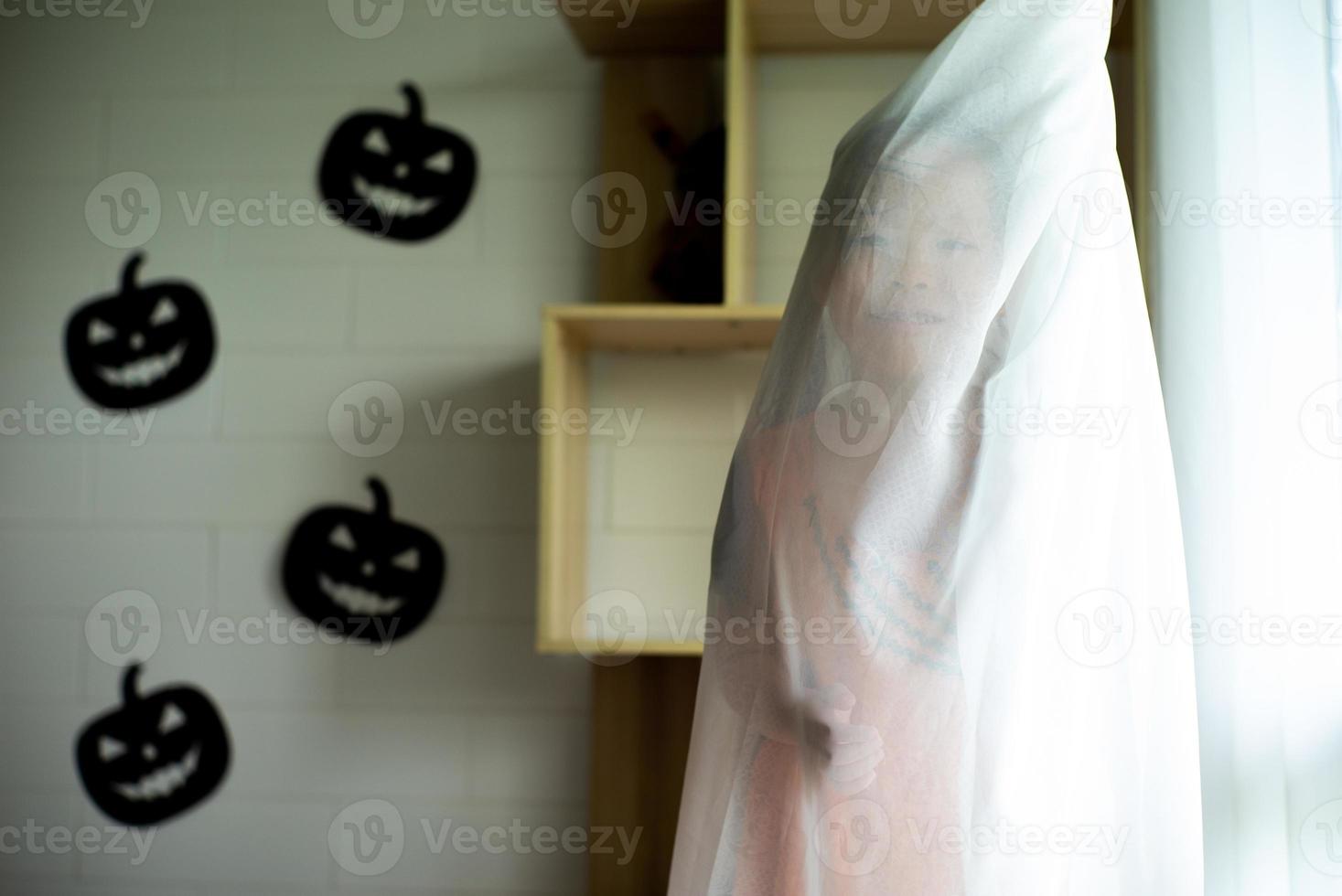 Porträt asiatisches kleines Mädchen, das im weißen sauberen Vorhang spielt und sich versteckt. foto