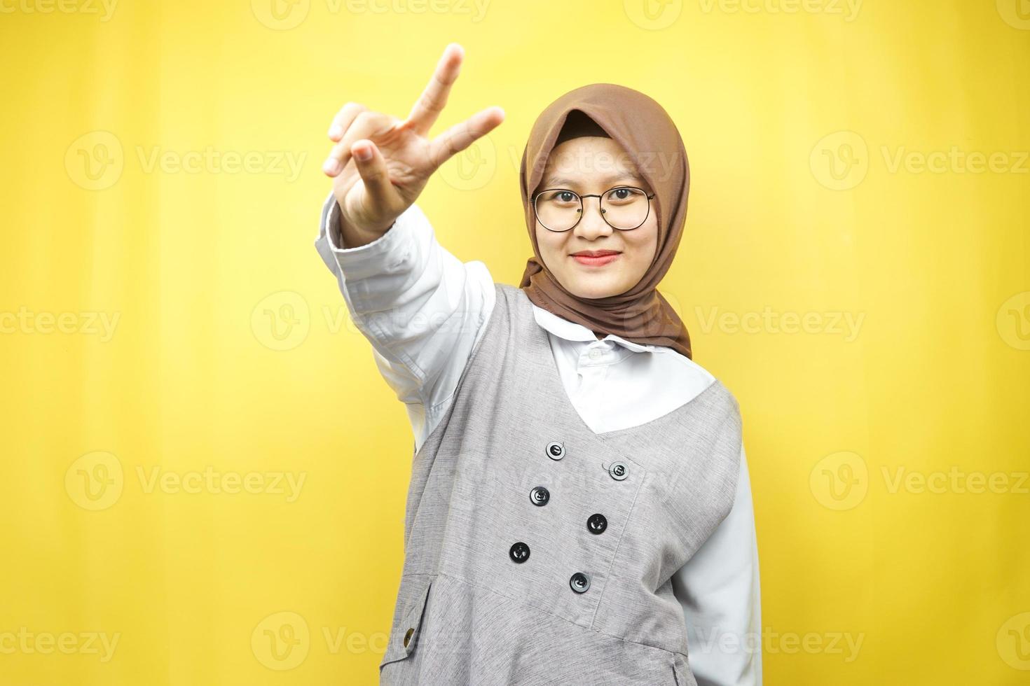 schöne junge asiatische muslimische frau schmollend mit v-signierten händen, ok, gute arbeit, vereinbarung, sieg, blick in die kamera einzeln auf gelbem hintergrund foto