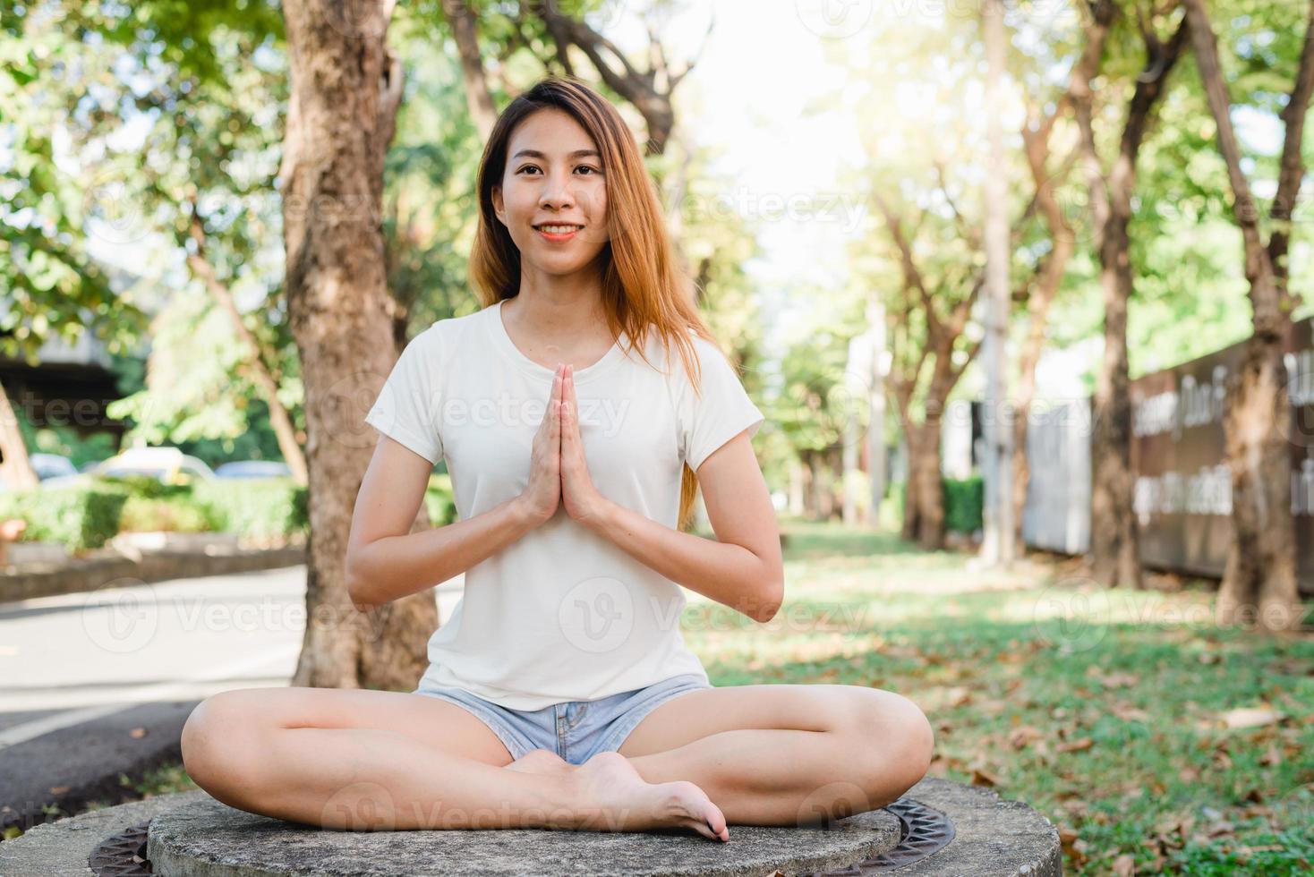 Yoga für junge asiatische Frauen im Freien bleibt ruhig und meditiert, während sie Yoga praktizieren, um den inneren Frieden zu erkunden. Yoga und Meditation haben gute Vorteile für die Gesundheit. Yoga Sport und gesunder Lebensstil Konzept. foto