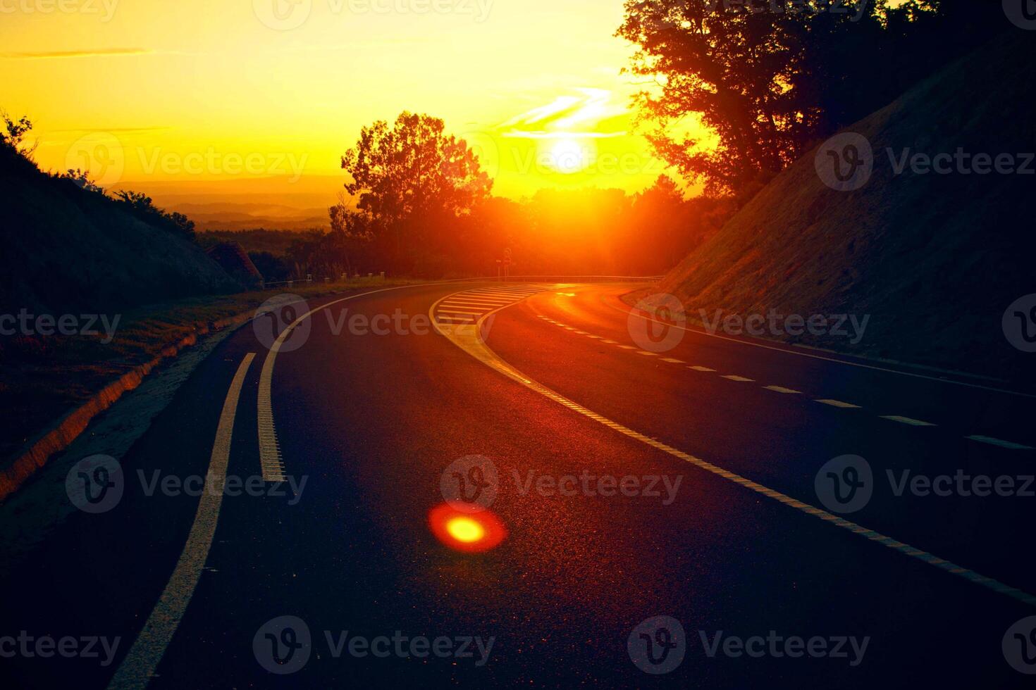 Sonnenuntergang orange in der Straßenspur schöne Straße, die in den Hügeln und Bergstraße Graslandstraße am Abend abbiegt. foto