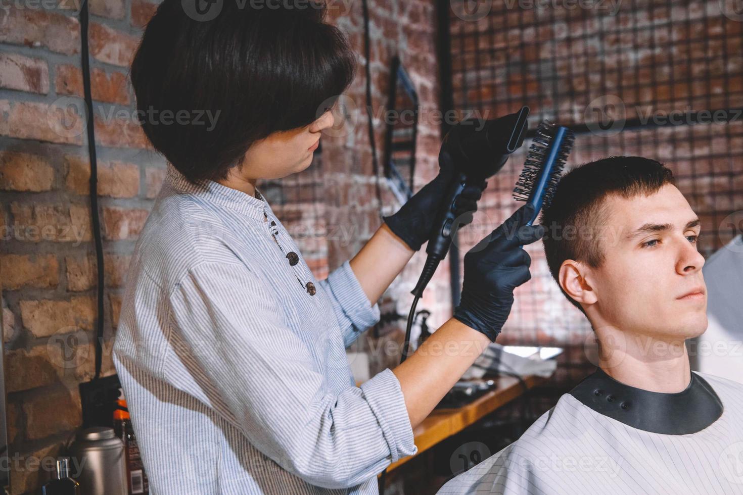 schöne Frau Friseur macht Haarschnitt für junge Mann im Friseurladen. Werbe- und Friseurkonzept foto