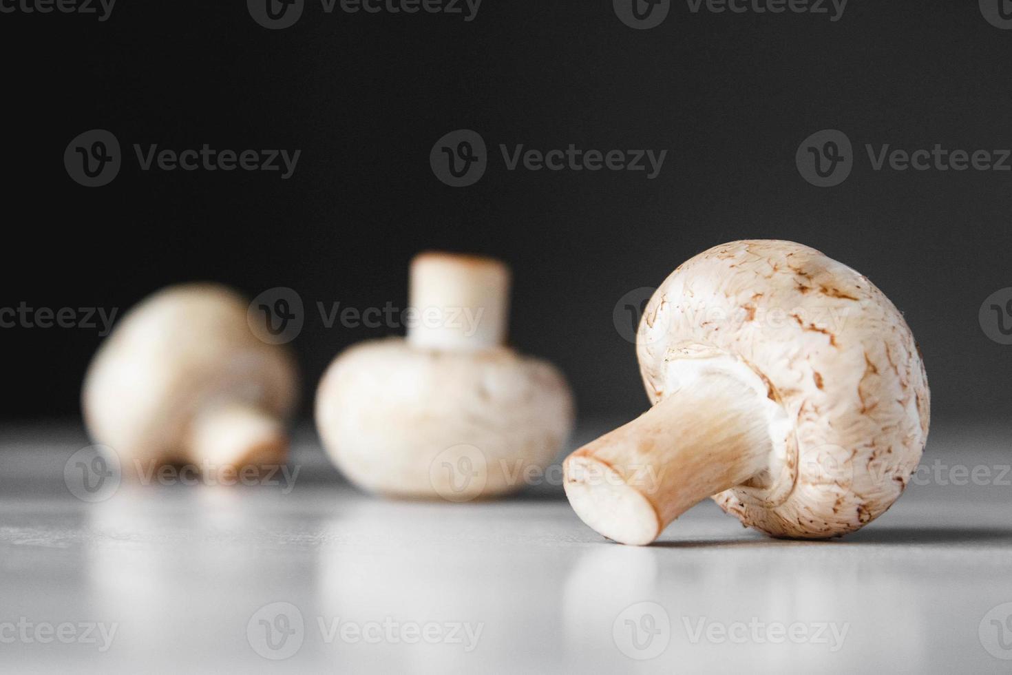 Champignons Champignons liegen in einer Reihe auf einem weißen Tisch auf dunklem Hintergrund foto