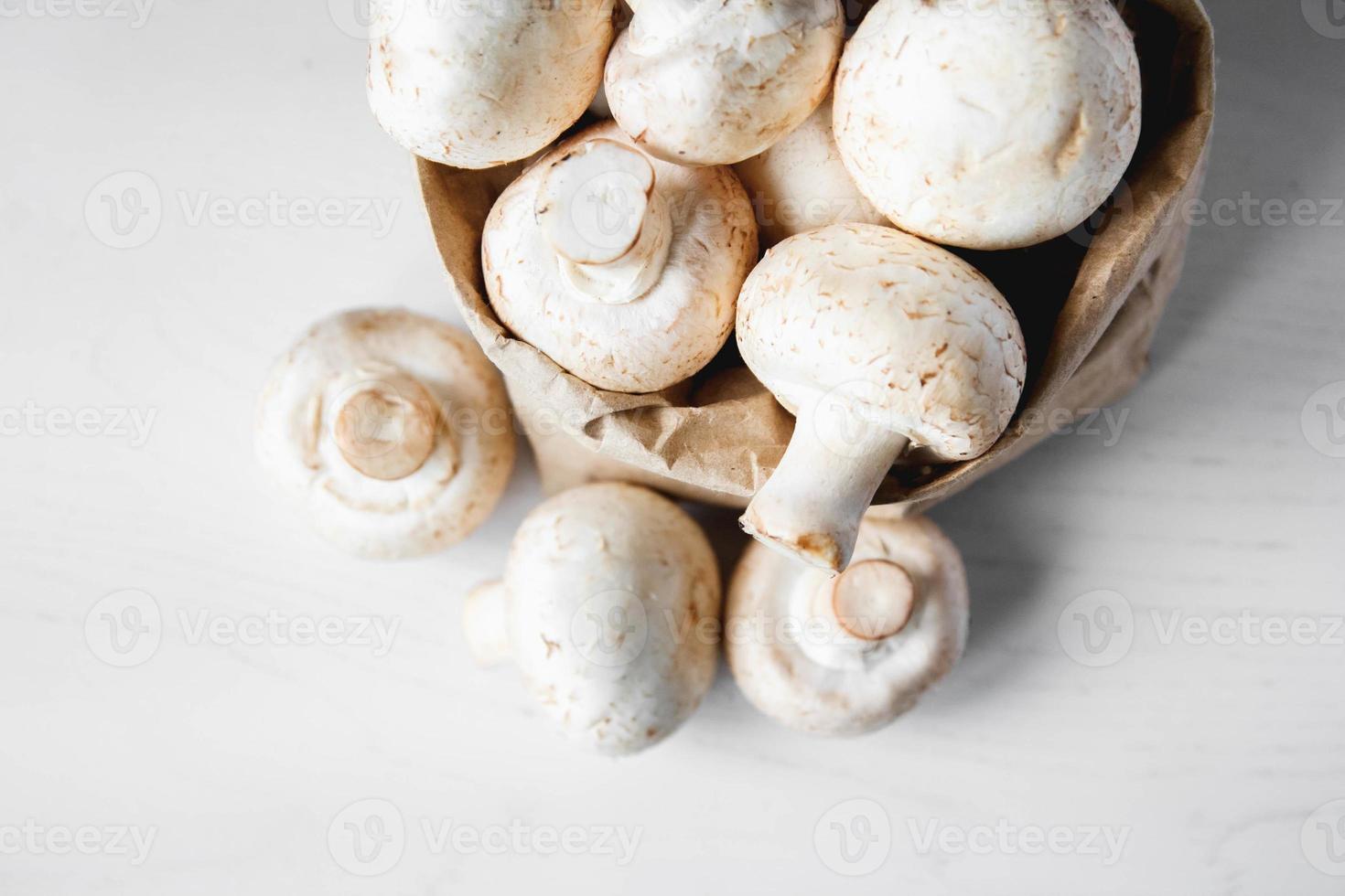 Champignons Champignons in Papiertüte auf einem weißen Holztisch foto