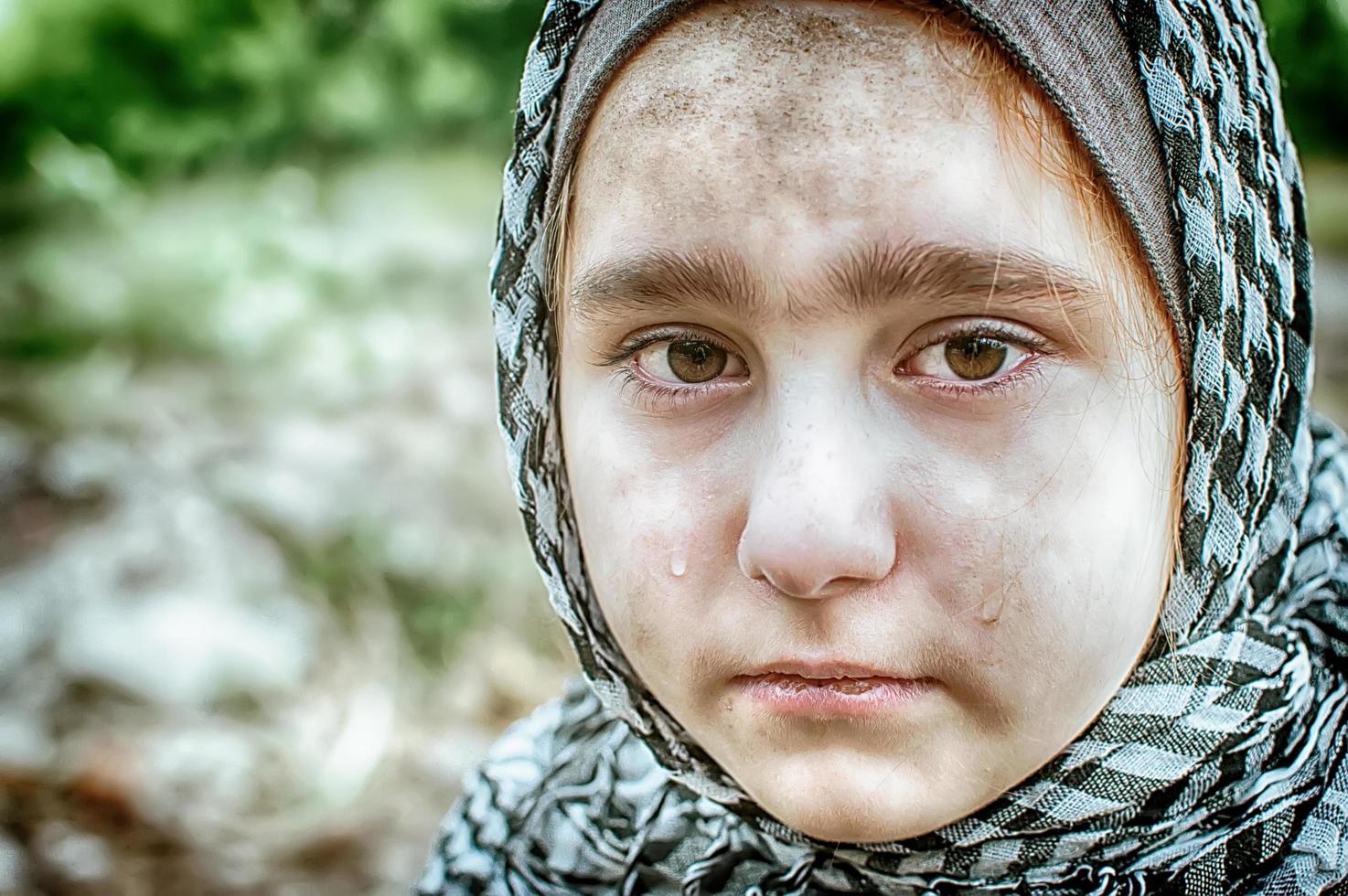 ein Flüchtlingskind im Krieg, ein muslimisches Mädchen mit schmutzigem Gesicht auf den Trümmern, das Konzept von Frieden und Krieg, das Kind weint und wartet auf Hilfe. foto