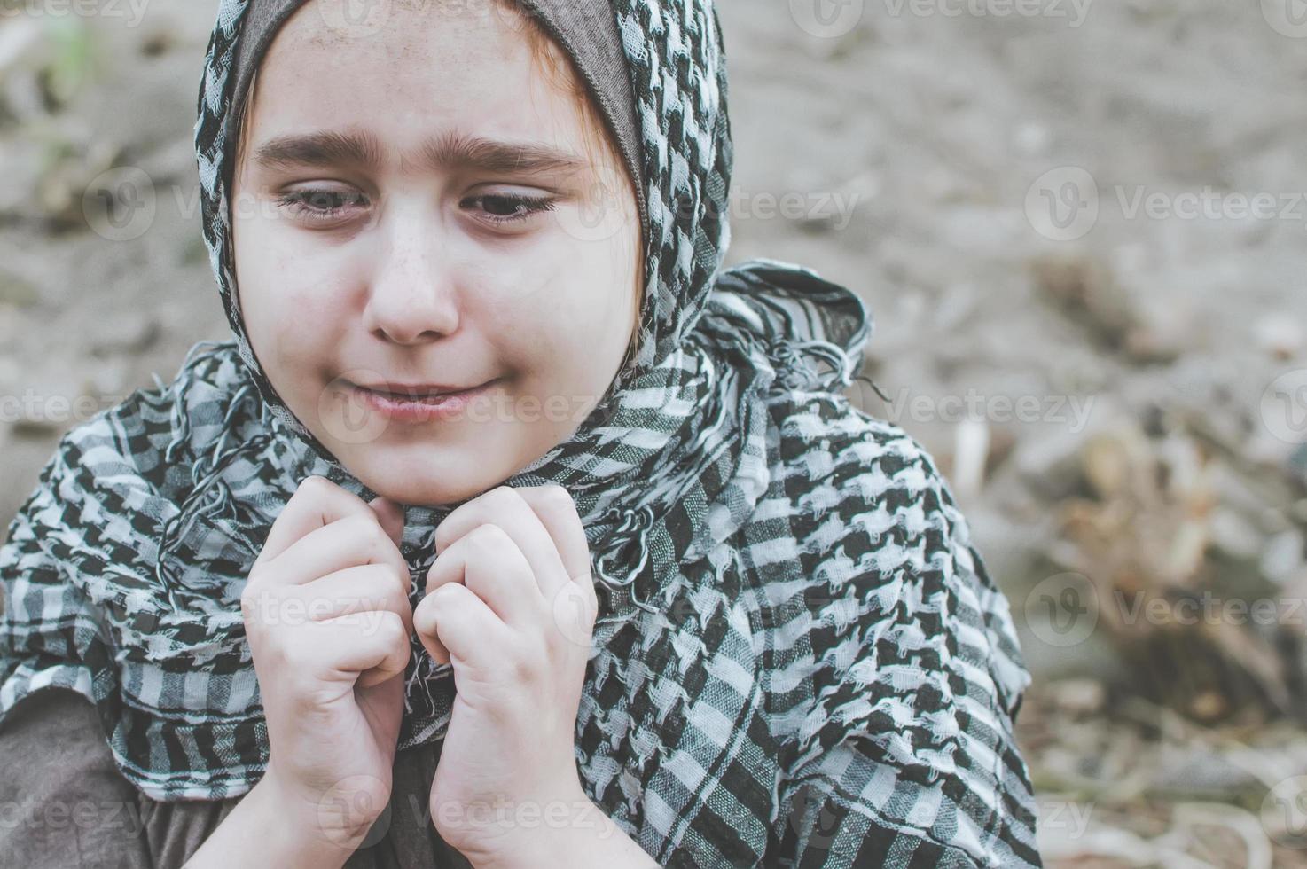 ein Flüchtlingskind im Krieg, ein muslimisches Mädchen mit schmutzigem Gesicht auf den Trümmern, das Konzept von Frieden und Krieg, das Kind weint und wartet auf Hilfe. foto