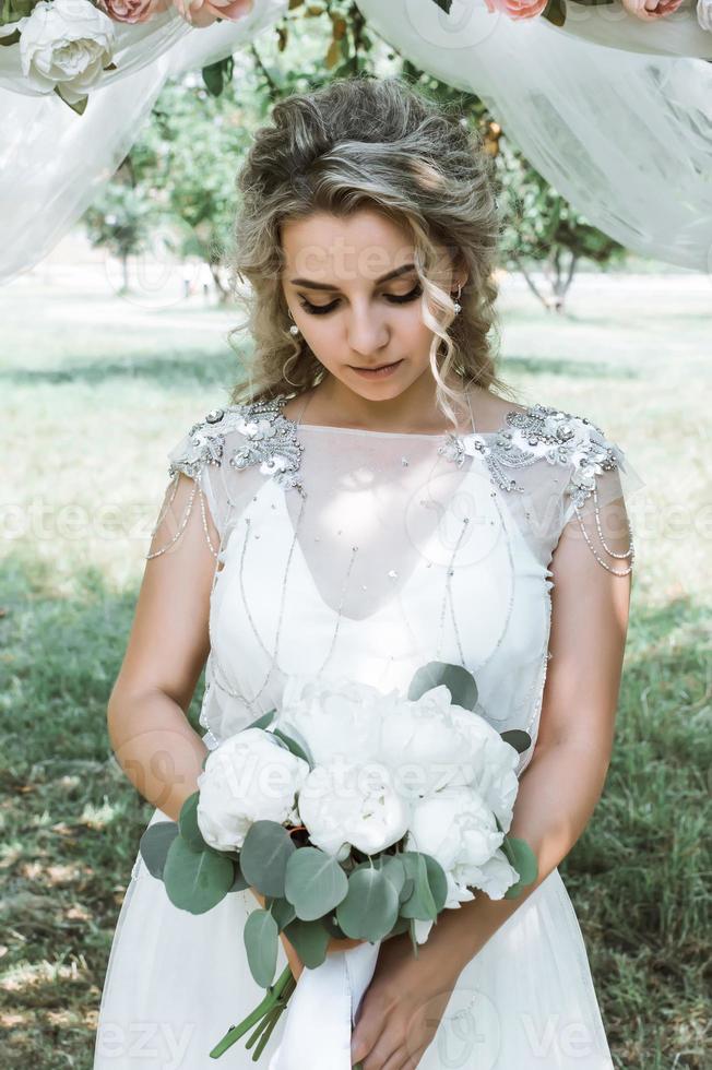 Braut mit einem Blumenstrauß in den Händen am Hochzeitstag. Hochzeitszeremonie. selektiver Fokus. Filmkorn. foto