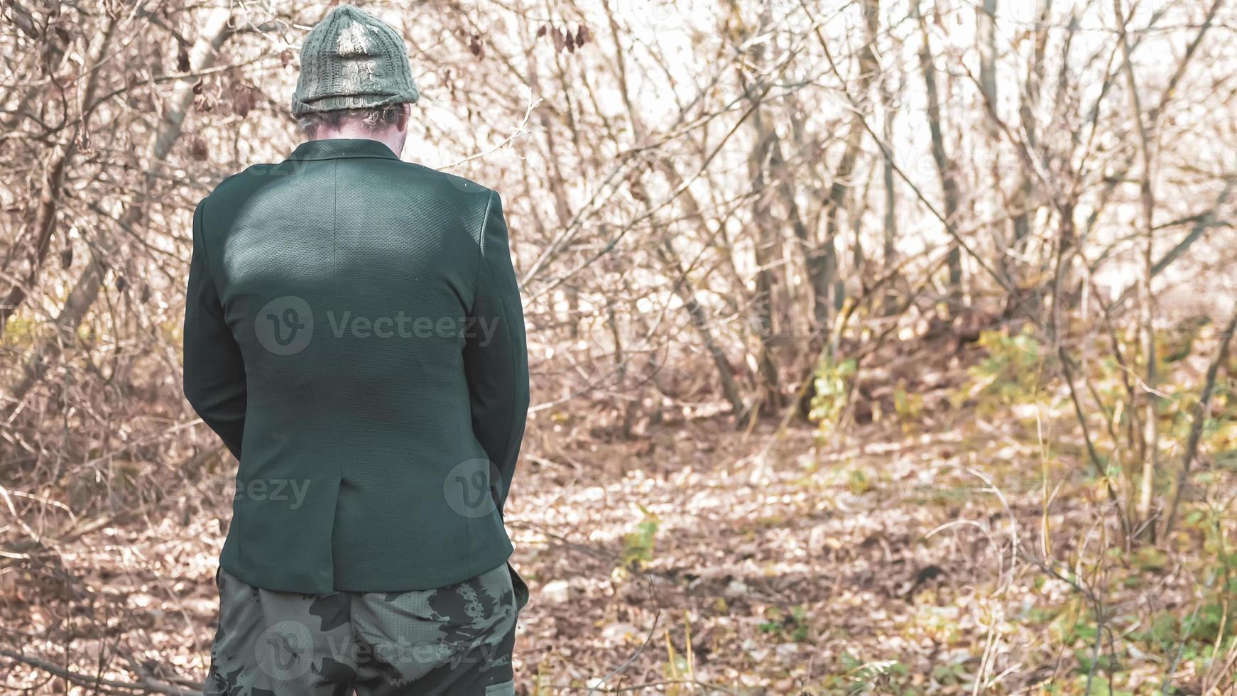 ein armer obdachloser alkoholiker in hut und anzug pisst in den müll geht auf die toilette für eine kleine krise in der modernen gesellschaft, das konzept des ungleichheitsproblems foto