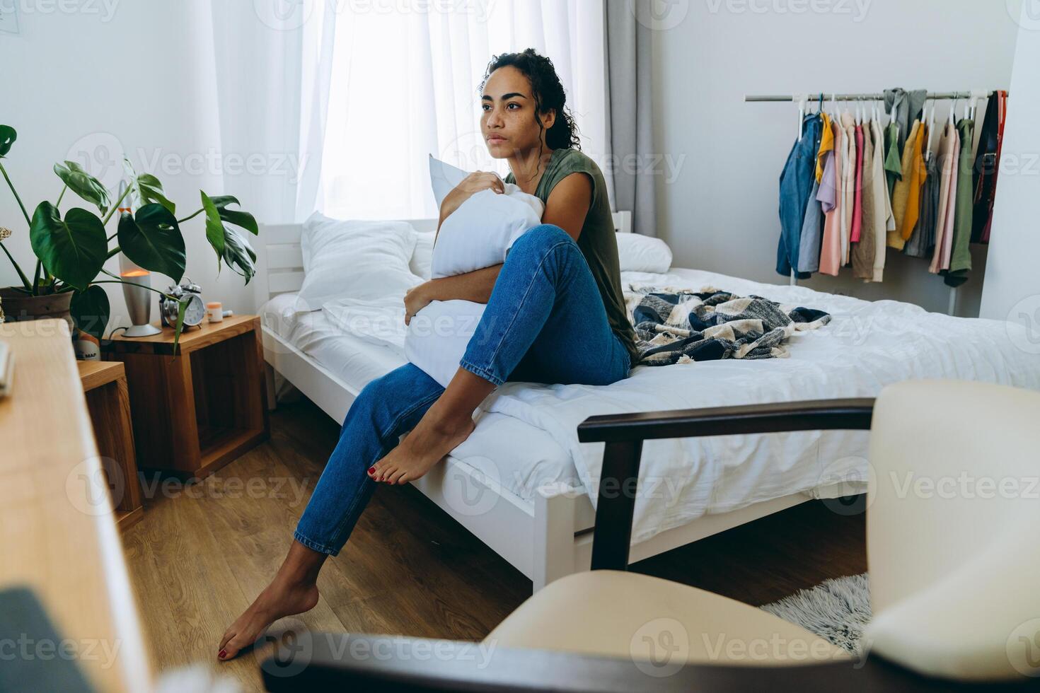 meditative Afrikanerin umarmt Kissen auf dem Bett foto