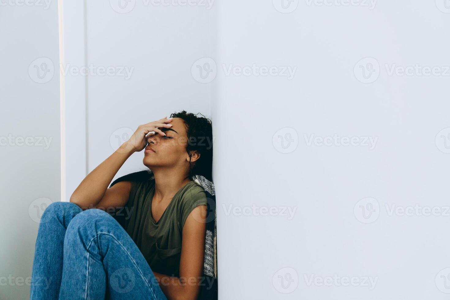 afrikanische müde frau, die ihr gesicht mit der hand auf dem boden bedeckt foto