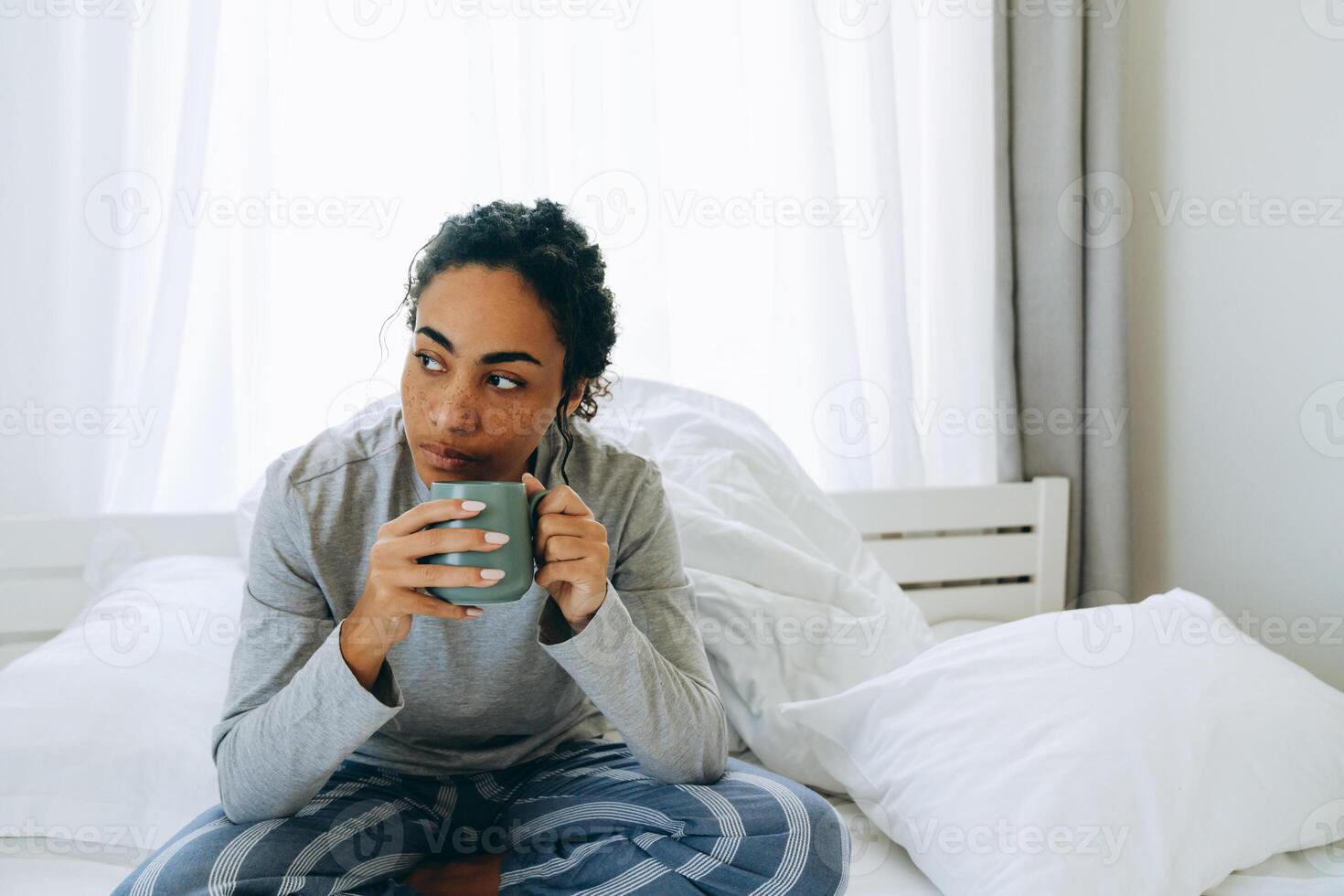 konzentrierte afrikanische frau, die kaffee trinkt und zur seite schaut foto