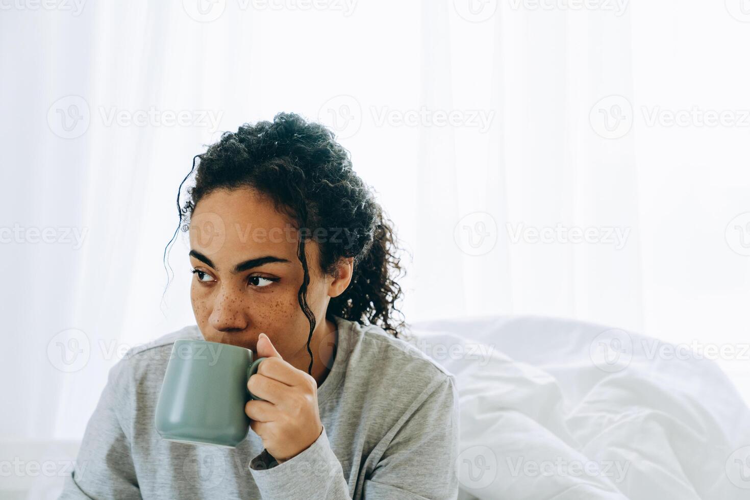 Porträt einer konzentrierten afrikanischen Frau, die Kaffee trinkt und zur Seite schaut foto