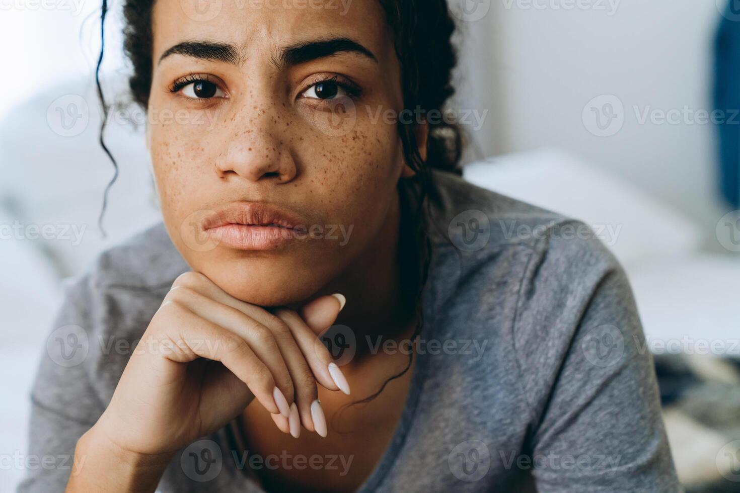 junge schwarze Frau runzelt die Stirn und schaut in die Kamera im Schlafzimmer foto