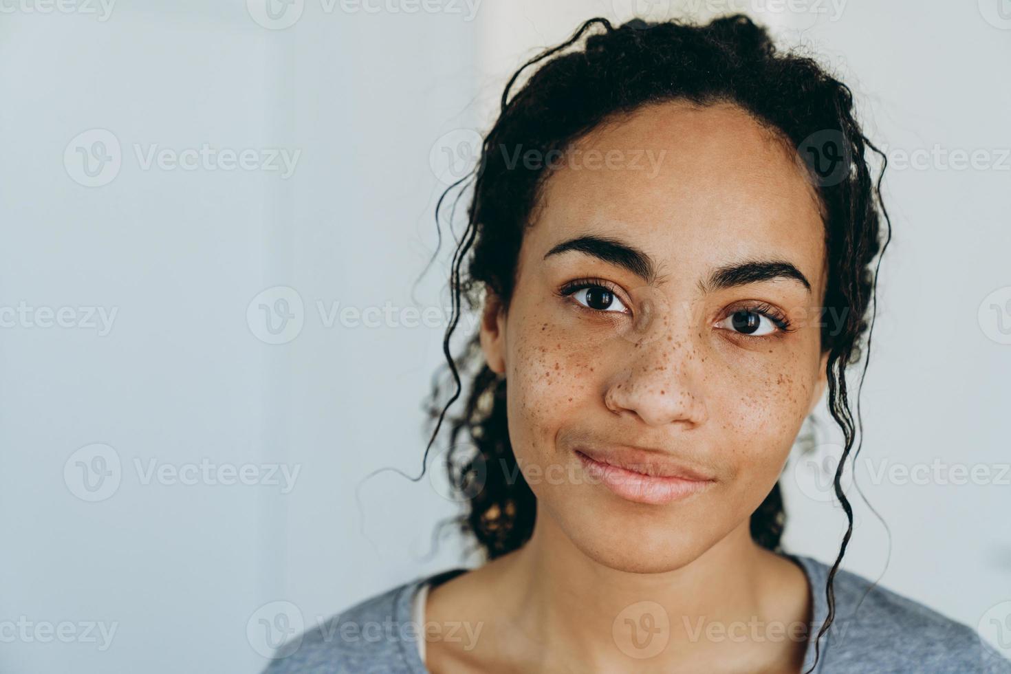 schwarze Frau, die lächelt und beiseite schaut, während sie Zeit zu Hause verbringt foto