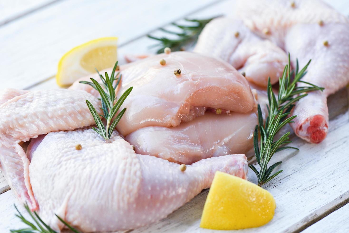 Brustflügel und -keulen rohes Hühnerfleisch mariniert mit Zutaten zum Kochen - frisches rohes Hühnerfleisch mit Rosmarin-Zitronen-Kräutern und Gewürzen foto