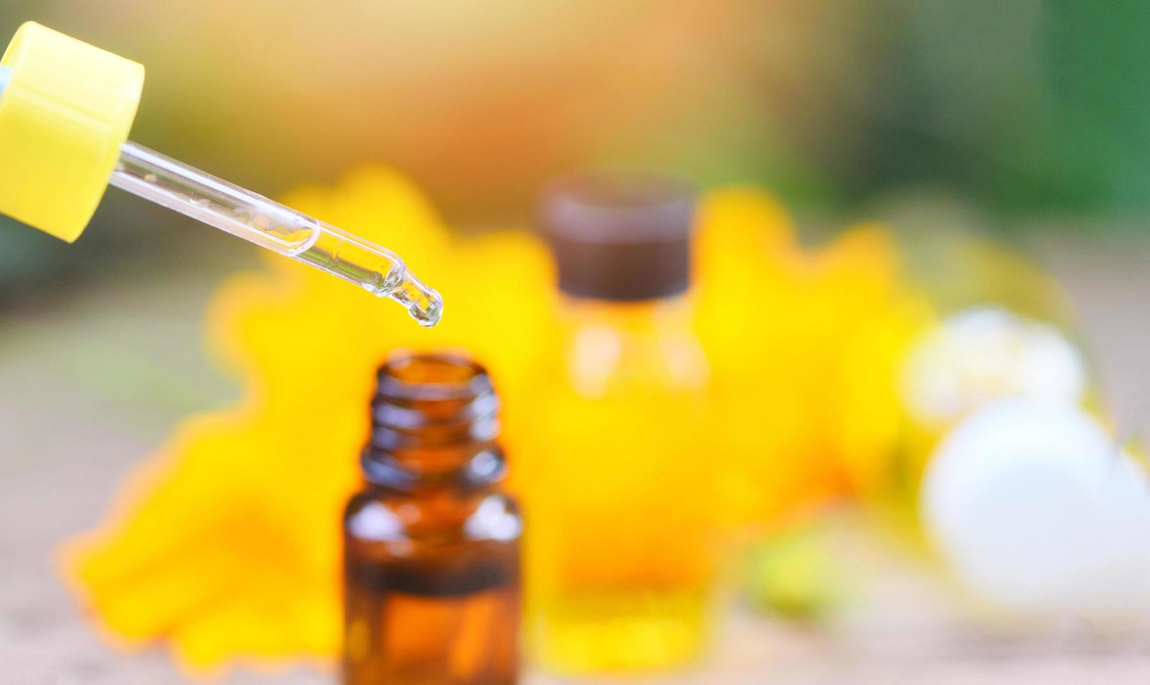 Aromatherapie Kräuterölflaschen Aromatropfer auf Glas mit Blume auf naturgrünem Hintergrund - ätherische Öle natürlich für Gesichts- und Körperschönheitsheilmittel auf Holztisch und Bio-Minimalis foto