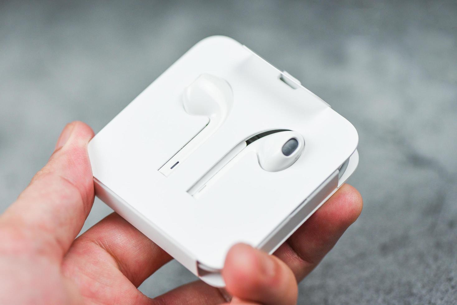 weiße kabellose Bluetooth-Kopfhörer oder Kopfhörer-Smartphone-Kopfhörer in Kunststoff-Aufbewahrungshülle einzeln in der Hand foto