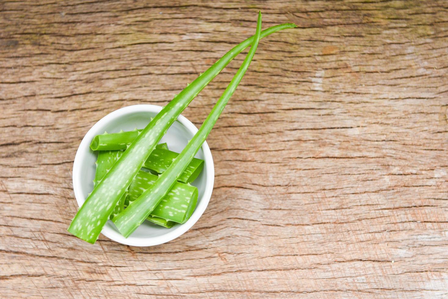 Aloe-Vera-Pflanzenscheibe in Schüssel auf rustikalem Holzhintergrund - Nahaufnahme von frischem Aloe-Vera-Blatt mit Gel-Naturkräutern und Kräuterarzneimitteln foto