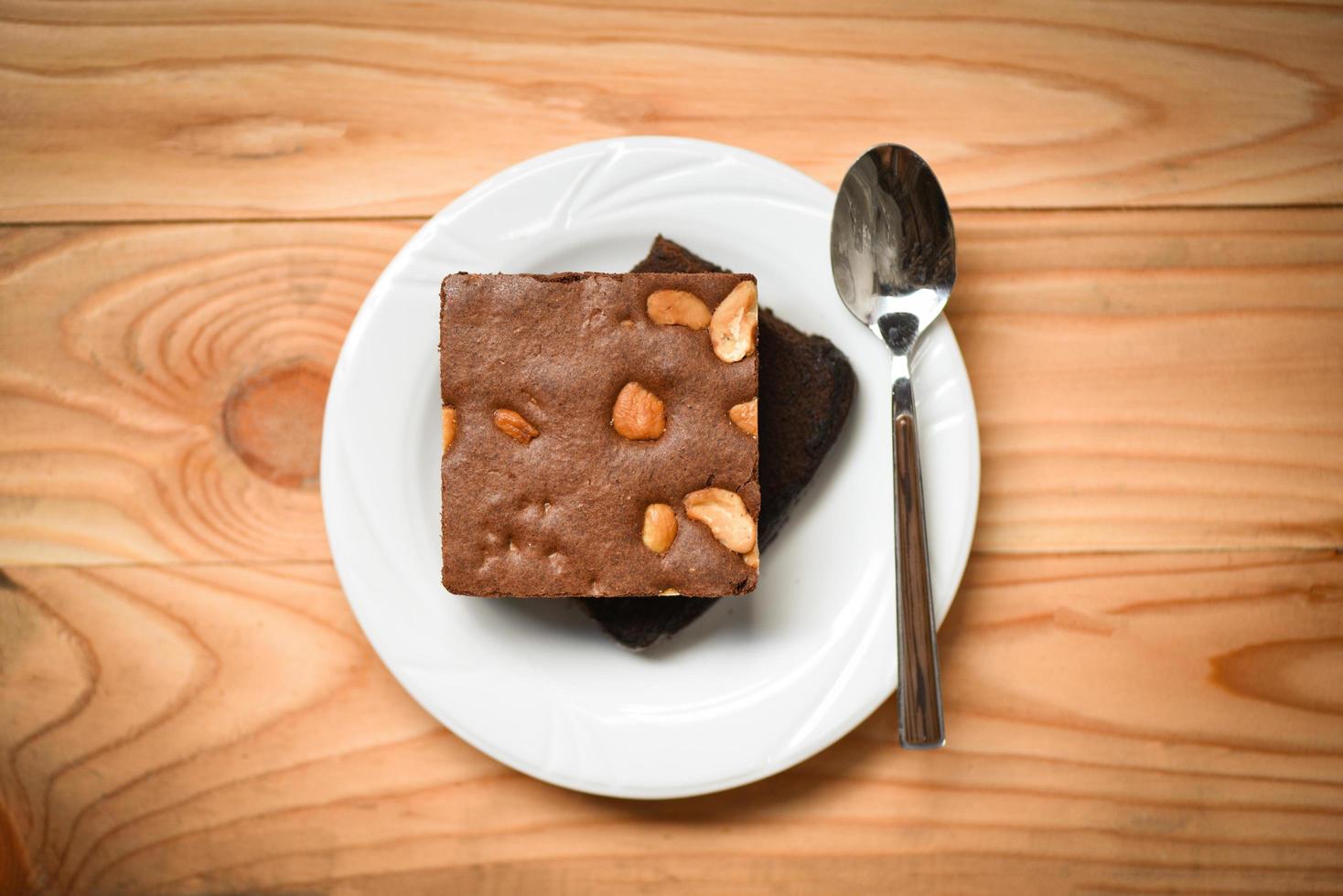 Brownies-Kuchen auf dem Tisch Schokoladenkuchen-Scheibe mit Nuss im Teller mit Löffel auf Holz foto