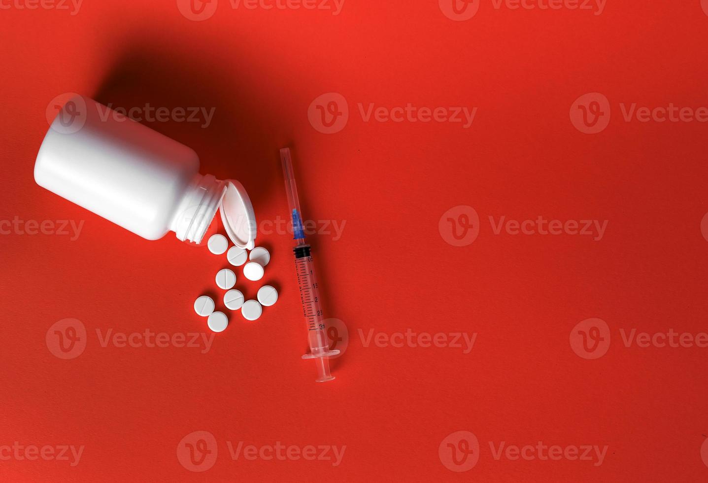 Pillen, die aus einem Plastikglas und einer Spritze auf rotem Hintergrund gegossen wurden, Draufsicht, Platz für Text foto