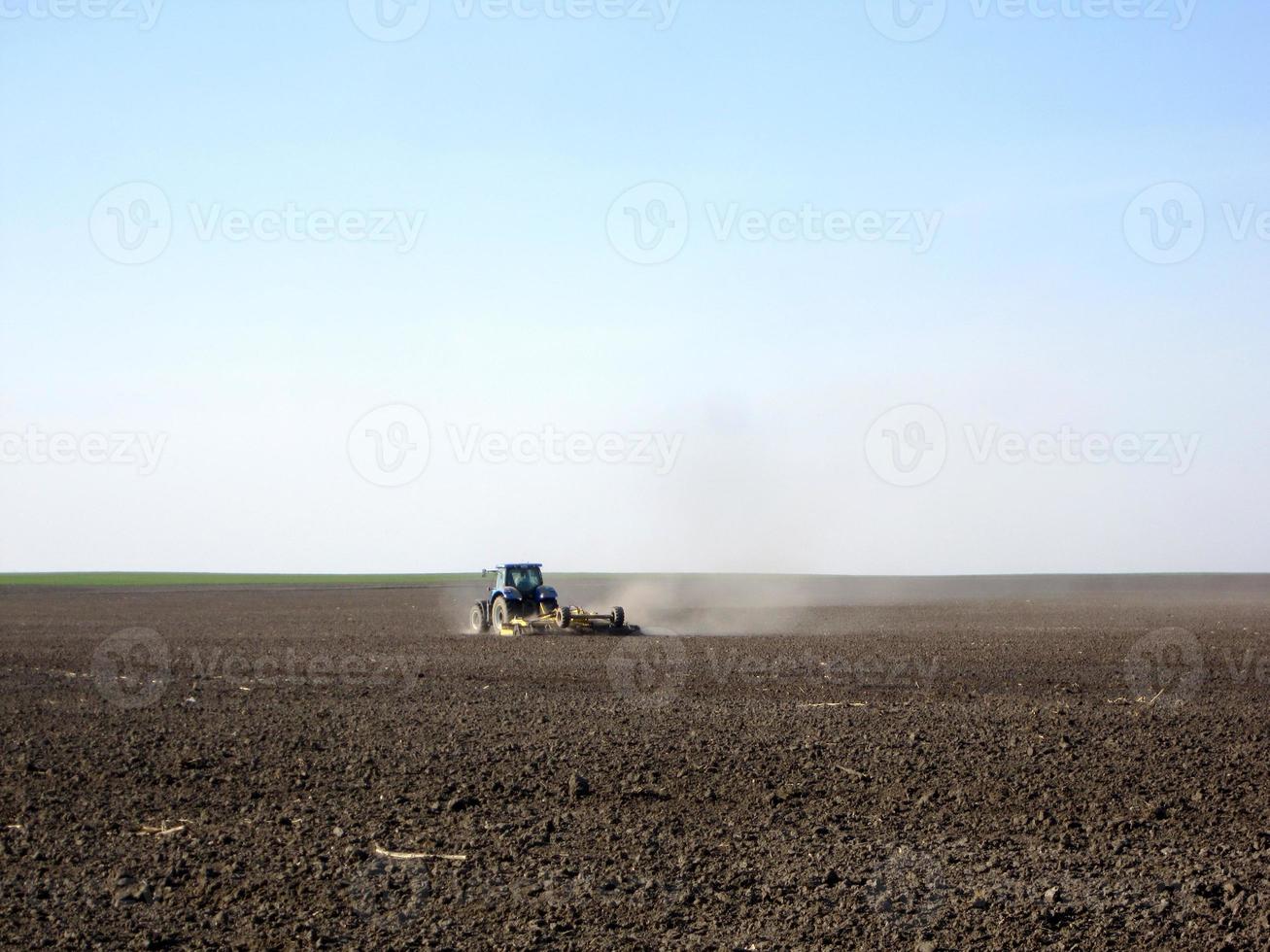 gepflügtes Feld mit Traktor in braunem Boden auf offener Landschaft Natur foto