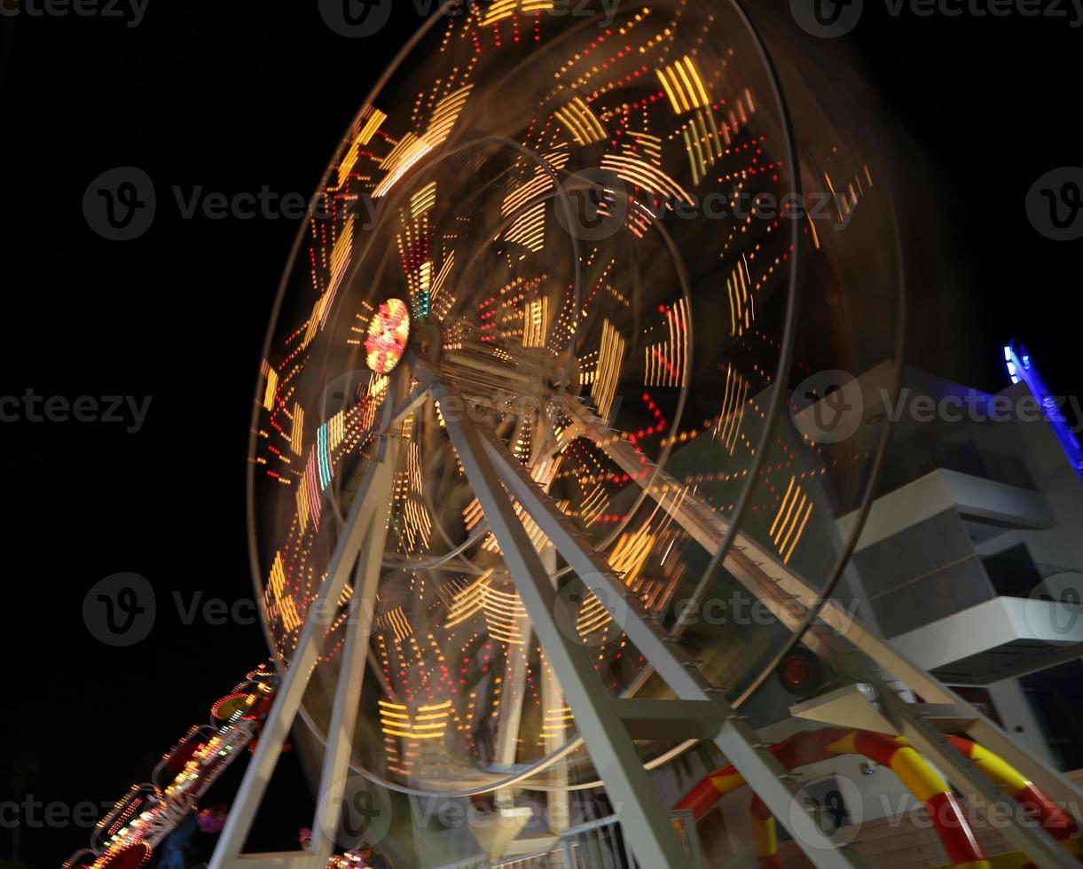 Das runde Riesenrad dreht sich in der schwarzen Nacht schnell foto