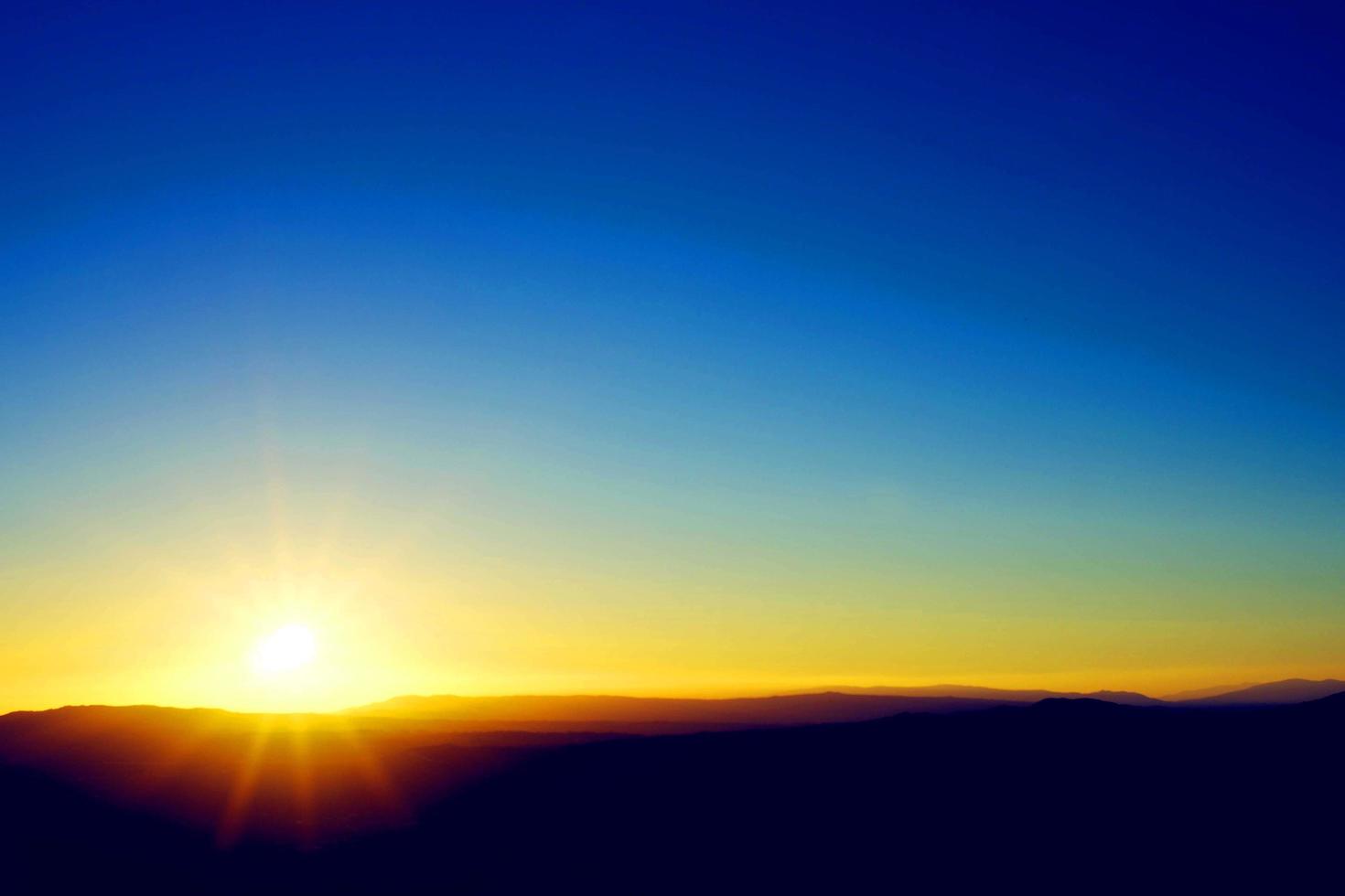 grün und meerblau und himmelblau schönes Meer und Sonnenuntergang mit großer gelber Sonne unter den Meeresoberflächenhügeln im Hintergrund. foto